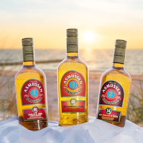 Drei Flaschen Asmussen Rum stehen auf einem weißen Sandstrand, umgeben von sanften Gräsern und einem Sonnenuntergang im Hintergrund.