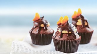 Drei köstliche Schokoladenmuffins mit einer glänzenden Schokoladenglasur und fruchtigen Orangenscheiben obendrauf.