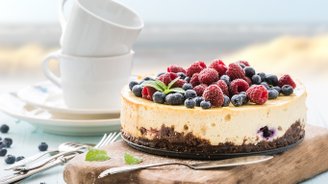 Ein köstlicher Käsekuchen mit frischen Himbeeren und Heidelbeeren, serviert auf einem rustikalen Holzbrett.