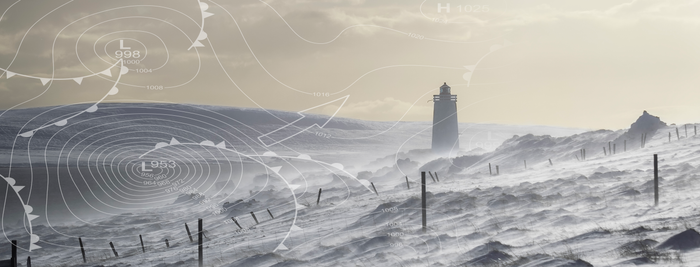 In einer winterlichen Szenerie zeigt sich ein Leuchtturm, umgeben von schneebedeckten Hügeln und starkem Wind.
